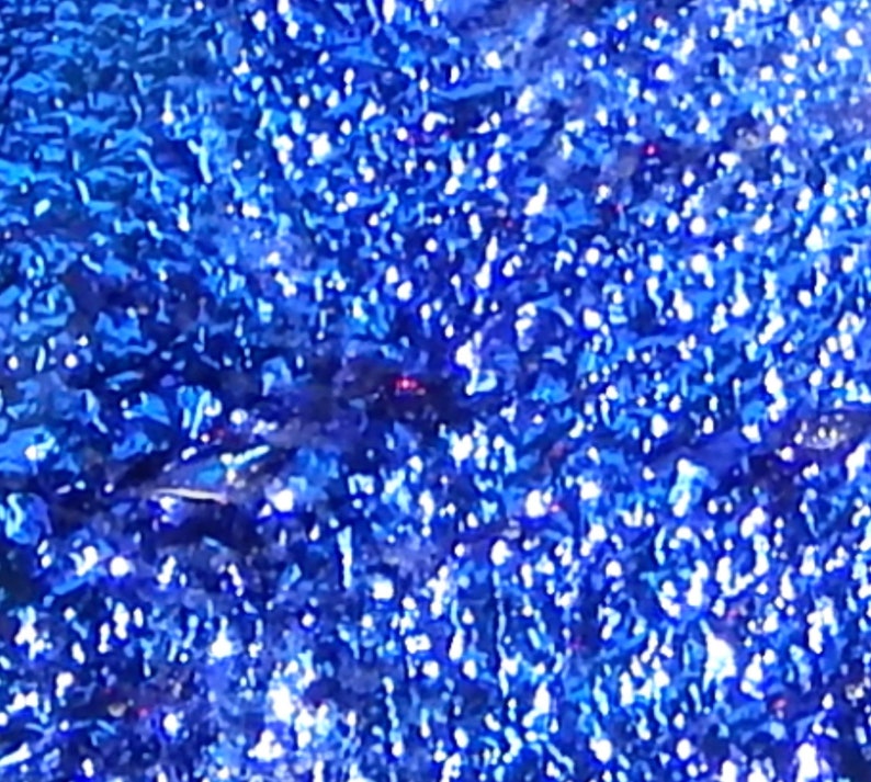Puede incluir: Primer plano de una tela azul con purpurina con un acabado brillante e iridiscente.