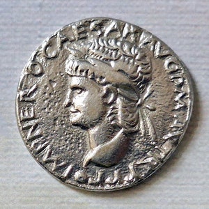 Könnte beinhalten: Silberne römische Münze mit dem Porträt einer Person mit einem Lorbeerkranz. Die Inschrift auf der Münze lautet "IMP CAESAR AVG F COS III PONT MAX TR P XIIII".