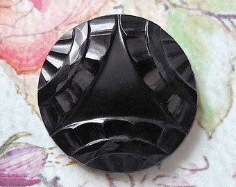 Zwarte glazen knop, Art Nouveau, antiek.  Ciruclar met een 3 sectie lint gebaseerd ontwerp, 4 tanden metalen lus schacht. c1890-1910.
