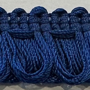 May include: A close-up of navy blue trim with a scalloped edge. The trim is made of a soft, woven fabric and is perfect for adding a touch of elegance to any project.