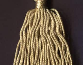 May include: A gold tassel with a long, flowing fringe. The tassel is made of a soft, woven material and has a knotted top.