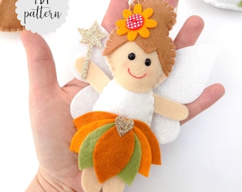 Könnte beinhalten: Eine Filz-Feenpuppe mit weißem Oberteil, orange-grünem Rock und glitzernden Flügeln. Die Fee hat braunes Haar, eine Blume auf dem Kopf und hält einen goldenen Sternenstab. Die Puppe ist handgefertigt und hat ein lächelndes Gesicht.