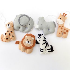 May include: A felt garland featuring six animal characters: a cheetah, elephant, rhinoceros, lion, zebra, and giraffe. The animals are all in different colours and have friendly faces.
