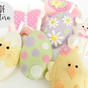 May include: A set of felt Easter decorations, including a chick, a bunny, a butterfly, and eggs with polka dots and flowers. The decorations are all white, pink, yellow, green, and purple.