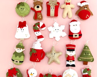 Puede incluir: Una colección de adornos navideños hechos a mano en varias formas, incluyendo un muñeco de nieve, un ángel y un hombre de jengibre. Los adornos son de fieltro y presentan colores festivos como el rojo, el verde y el dorado. Cada adorno tiene un lazo para colgar.