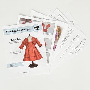 May include: A PDF sewing pattern for an 18-inch doll outfit, featuring a red jumper, a white blouse, and a matching bolero jacket. The pattern is titled "Harbor Fair" and is from Bringing Joy Boutique.