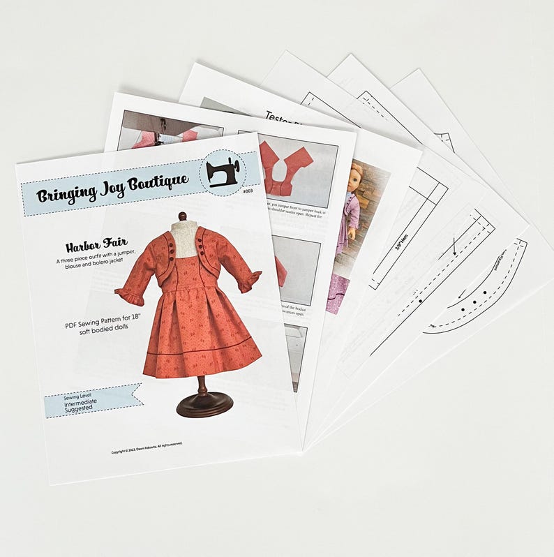 May include: A PDF sewing pattern for an 18-inch doll outfit, featuring a red jumper, a white blouse, and a matching bolero jacket. The pattern is titled "Harbor Fair" and is from Bringing Joy Boutique.