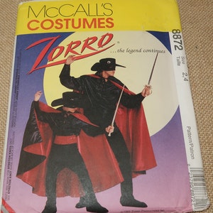 May include: A sewing pattern for a Zorro costume. The pattern includes instructions for making a black shirt, red cape, and a mask. The pattern is for sizes 2-4. The text on the pattern reads "Zorro... the legend continues".