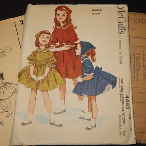 May include: A vintage McCall's printed pattern envelope 4465 for a girl's dress, babushka, and petticoat. The cover features illustrations of three figures wearing dresses in yellow, red, and blue with matching headscarves and white lace trim.