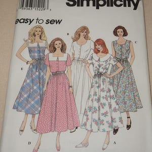 May include: Simplicity sewing pattern for five different dresses. The pattern includes a white dress with a button-up front, a pink dress with white polka dots, a floral print dress, a blue and white plaid dress, and a blue floral print dress. The pattern is labeled "easy to sew".