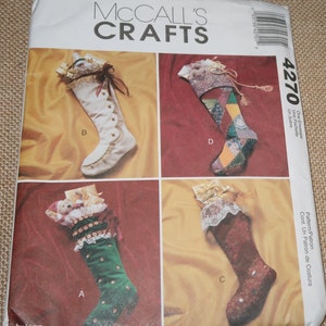 May include: McCall's Crafts pattern envelope featuring four Christmas stocking designs. The stockings vary in color and style, including a white boot-shaped stocking with button details and a green velvet stocking with embellishments.