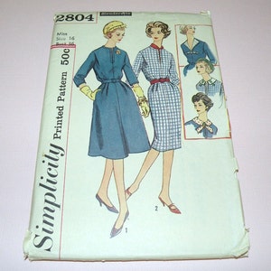 May include: A vintage Simplicity 2804 Slenderette sewing pattern envelope featuring illustrations of two dress styles. One dress is solid blue with a belt, and the other is a blue and white checkered pattern. Includes text: Simplicity, 2804, Miss Size 16, Bust 36.