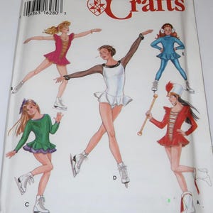May include: A Simplicity Crafts sewing pattern envelope featuring illustrations of five different outfits including a pink skating dress, a white skating dress with black sleeves, a blue skating outfit, a green skating dress, and a red marching band uniform.