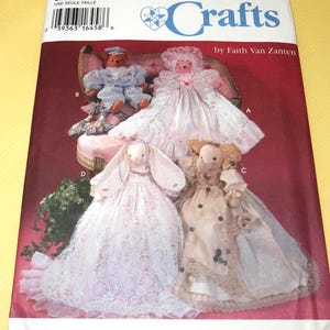 May include: Simplicity Crafts sewing pattern featuring doll designs. The pattern includes instructions for creating various dolls, including a bear, a bunny, and other fabric dolls. The cover displays the finished dolls in different outfits.