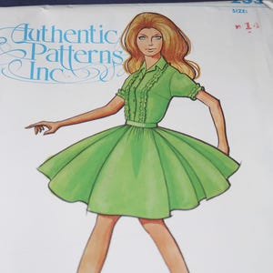 May include: An illustration of a woman wearing a green dress with a flared skirt and short sleeves. The dress has a button-up front and decorative trim. The text "Authentic Patterns Inc" is visible in the upper left corner. The size is indicated as 14.