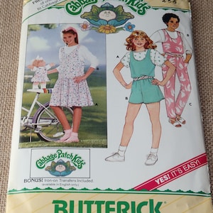 May include: A vintage sewing pattern for Cabbage Patch Kids clothing. The pattern includes instructions for making a dress, a jumpsuit, and a pair of pants. The pattern is for sizes 4-5-6. The pattern is from the brand Butterick.
