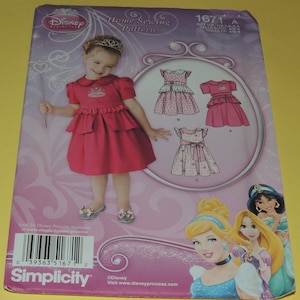 May include: A Simplicity sewing pattern for a princess dress. The pattern is for sizes 1/2-4. The pattern includes three different dress styles. The pattern is from Disney Princess.