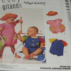 May include: Baby Gitano sewing pattern featuring baby rompers and a sun hat. The pattern includes multiple romper designs in pink, blue, and yellow, with button closures and ruffle details. The pattern is labeled with the number 6551.