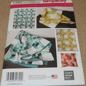 May include: Simplicity sewing pattern featuring quilt designs. The pattern includes various quilt block arrangements in shades of teal, yellow, and red. The pattern is designed and printed in the USA. The pattern is from Elizabeth Hartman Quilts.