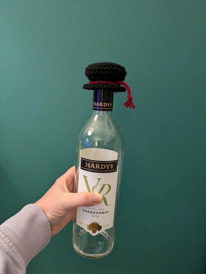 K&ouml;nnte beinhalten: Eine klare Glasflasche Hardy's Varietal Range Chardonnay Wein mit einem schwarzen H&auml;kelhut auf der Oberseite. Die Flasche hat ein wei&szlig;es Etikett mit dem Text "Hardy's Varietal Range Chardonnay 2023" und dem Text "Est'd 1832".