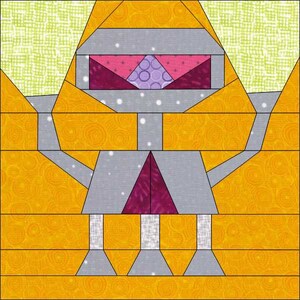 May include: A patchwork quilt block featuring a robot design. The robot is made of gray, purple, and pink fabric. The background is yellow.