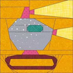 May include: A quilt block pattern featuring a gray, white, and pink robot with a teal eye. The robot is surrounded by a yellow background with a swirl pattern.