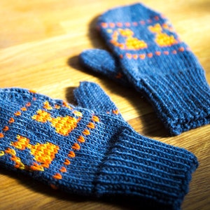 May include: A pair of blue knitted mittens with orange and yellow geometric patterns. The mittens are made of a soft, warm material and are perfect for keeping your hands warm in the winter.