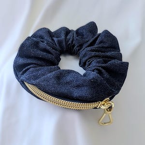 May include: A dark blue denim scrunchie with a gold zipper and a gold zipper pull.