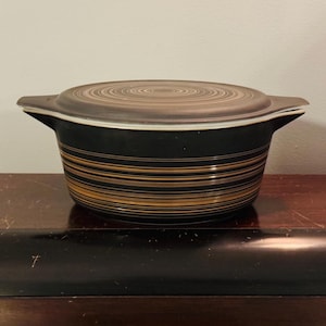 May include: A black and brown striped casserole dish with a lid. The lid has a swirl pattern.