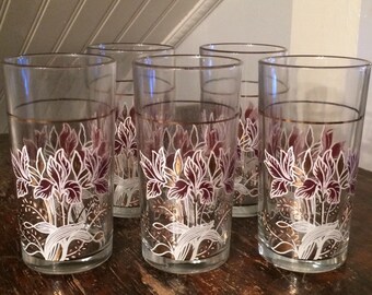 May include: Set of six clear glass tumblers with a gold rim and a floral design. The flowers are white with purple accents.