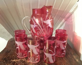 May include: A set of eight ruby red glass tumblers and a matching pitcher with a frosted design of flying geese and reeds.