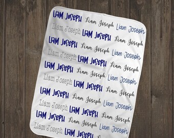 May include: White baby blanket with the name "Liam Joseph" repeated in blue lettering.