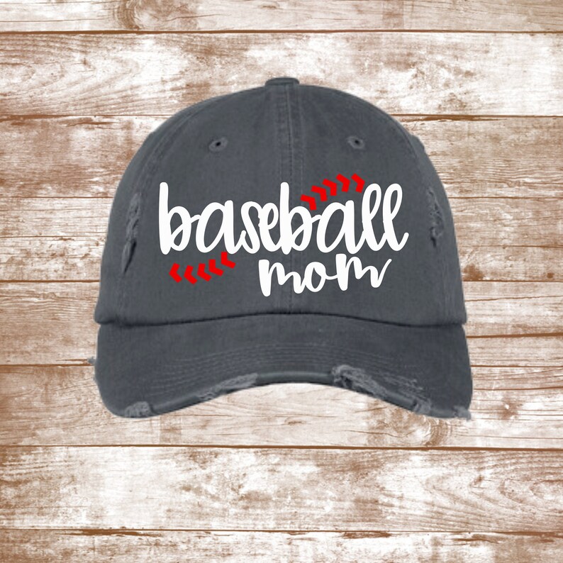 K&ouml;nnte beinhalten: Eine graue, abgenutzte Baseballkappe mit wei&szlig;em Text, der "baseball mom" lautet, und roten N&auml;hten in Form eines Baseball-Stichs.
