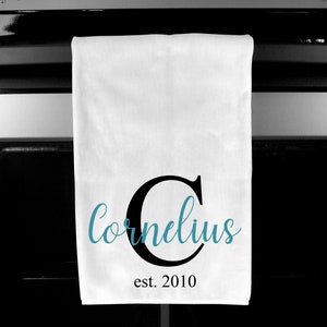 May include: White kitchen towel with a black letter C and the text "Cornelius est. 2010" in black script. The letter C is filled with a teal blue color.