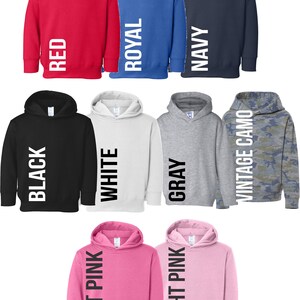 May include: A set of ten hooded sweatshirts in various colours, including red, royal blue, navy, black, white, grey, hot pink, light pink, and camouflage. Each sweatshirt has a vertical word printed on the side, such as "RED", "ROYAL", "NAVY", "BLACK", "WHITE", "GREY", "HOT PINK", "LIGHT PINK", and "VINTAGE CAMO".