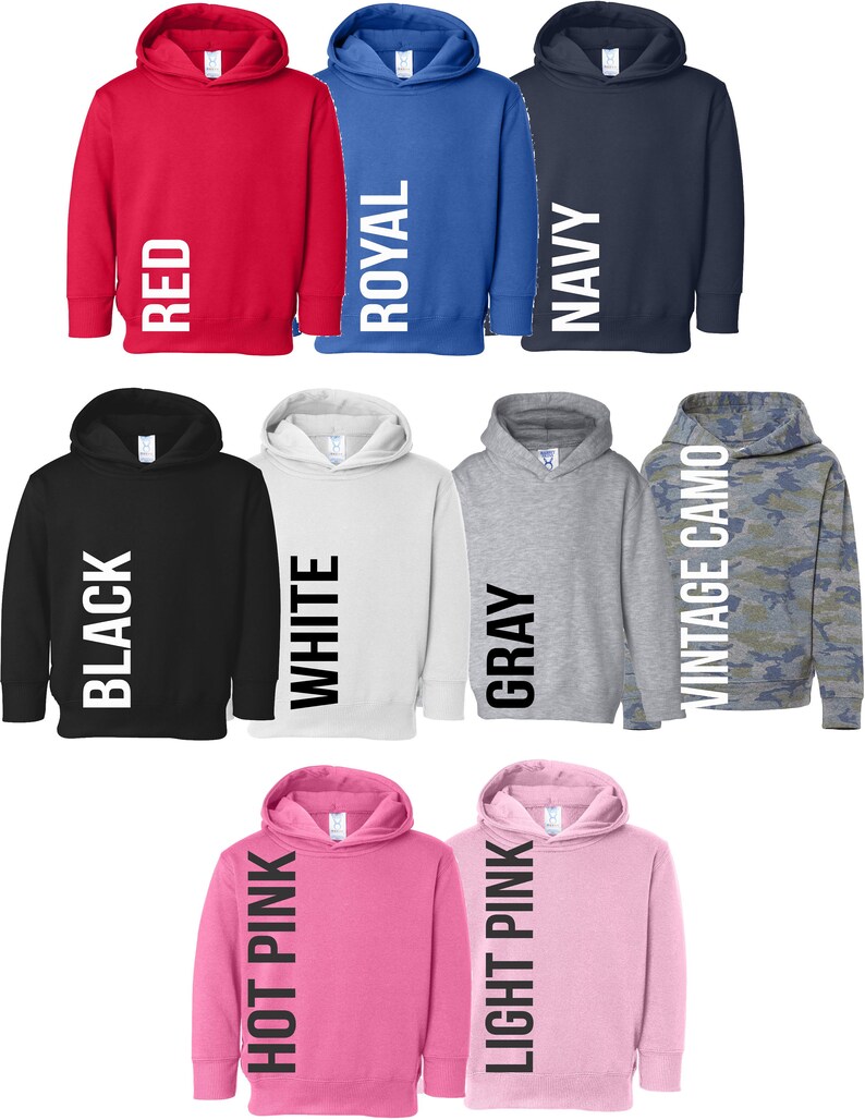 May include: A set of ten hooded sweatshirts in various colours, including red, royal blue, navy, black, white, grey, hot pink, light pink, and camouflage. Each sweatshirt has a vertical word printed on the side, such as "RED", "ROYAL", "NAVY", "BLACK", "WHITE", "GREY", "HOT PINK", "LIGHT PINK", and "VINTAGE CAMO".