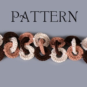 May include: A crocheted bracelet made of brown, beige, and cream colored yarn. The bracelet is made of a series of connected loops and has metal clasps on each end.