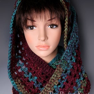 Peut inclure: Un col en crochet avec une capuche dans les tons bordeaux, turquoise et vert. Le col est réalisé avec un point de dentelle et est porté par un mannequin. Le texte "The Perfect Knot Crochet and More 2013" est visible en bas de l'image.