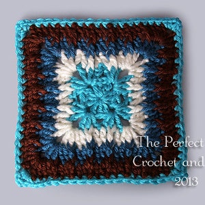 Puede incluir: Un cuadrado tejido a crochet con un borde azul, blanco y marrón. El centro del cuadrado es una flor azul tejida a crochet.