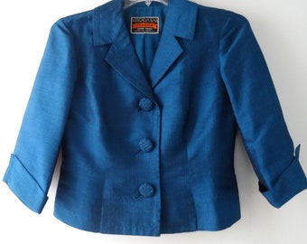 May include: A teal blue blazer with three buttons and a label that reads "MEDOS" in orange text.