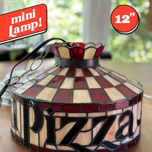 May include: A 12-inch stained glass pizza lamp with a red and white checkered pattern and the word "pizza" in black lettering.