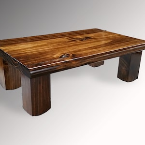May include: A small, rectangular wooden step stool with a dark brown stain. The stool has four sturdy legs and a smooth, polished surface. The dimensions are approximately 18 inches long, 10 inches wide, and 8 inches high.