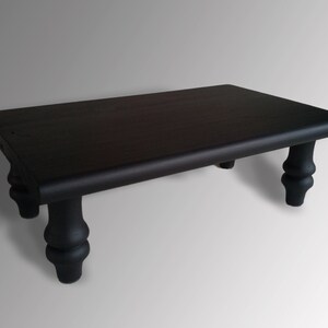 May include: A black wooden coffee table with a rectangular top and four turned legs.