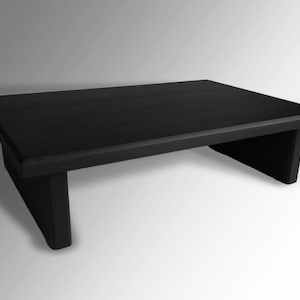 May include: A black wooden riser with a rectangular top and two supports. The riser is made of solid wood and has a smooth finish.