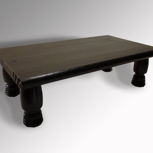 May include: A dark brown wooden table with four turned legs. The table top is rectangular and has a smooth, polished finish.