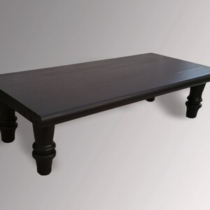 May include: A dark brown wooden coffee table with a rectangular top and four turned legs.