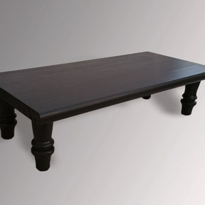May include: A dark brown wooden coffee table with a rectangular top and four turned legs.