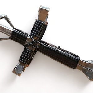 May include: A black wire-wrapped cross made from two horseshoe nails.