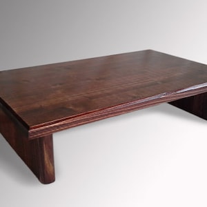 May include: A dark brown wooden riser with a rectangular top and two supports. The riser is made of solid wood and has a smooth finish.