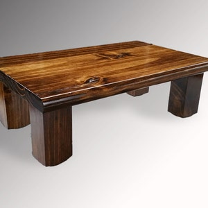 May include: A dark brown wooden platform with a rectangular top and four legs. The platform is made of solid wood and has a natural finish.